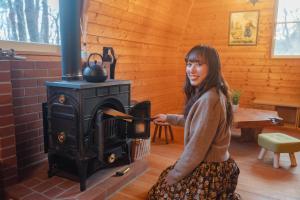 a woman is sitting in front of a stove at -Secret Bloom- 可愛いがギュッと詰まったパン屋さんとサファリパークに近い黄色いコテージ in Nasu-yumoto