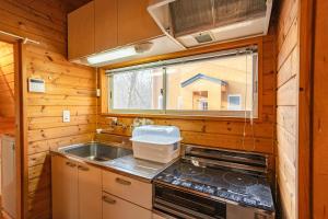 a kitchen with a stove and a sink and a window at -Secret Bloom- 可愛いがギュッと詰まったパン屋さんとサファリパークに近い黄色いコテージ in Nasu-yumoto