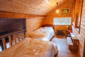 a bedroom with two beds in a wooden cabin at -Secret Bloom- 可愛いがギュッと詰まったパン屋さんとサファリパークに近い黄色いコテージ in Nasu-yumoto