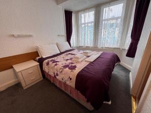a bedroom with a bed with purple sheets and a window at RideSide Hotel in Blackpool