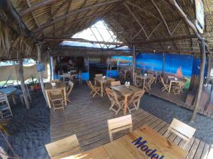 un restaurante al aire libre con mesas y sillas de madera en Hotel El Delfin, en Monterrico