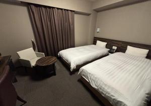 a hotel room with two beds and a chair at Dormy Inn Premium Hakata Canal City Mae in Fukuoka