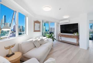 a living room with a white couch and a flat screen tv at Honeymoon Retreat in Gold Coast