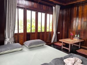 a bedroom with a bed and a table and windows at BanYat Farm Stay in Ban Bang Phae