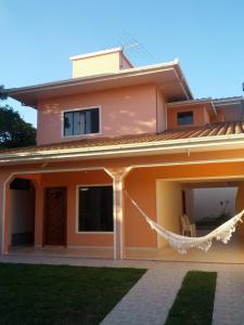 a house with a hammock in front of it at Casa 3Jotas in Garopaba