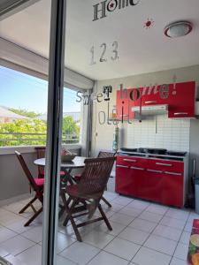 a kitchen with red cabinets and a table with chairs at Le Nid du rocher in Le Diamant +1 photo