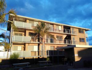 an apartment building with palm trees in front of it at Narooma Palms Holiday Apartments in Narooma