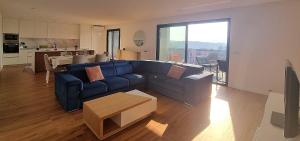a living room with a blue couch and a kitchen at Sisters Apartamento -200m2 centre ville in Ponte da Barca