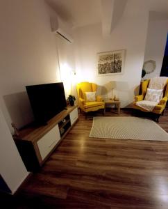 salon z telewizorem z płaskim ekranem i żółtymi krzesłami w obiekcie Cloud9Rest & Fly w mieście Koropi