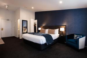 a bedroom with a large bed and a blue wall at Gilmer Apartment Hotel in Wellington +123 photos