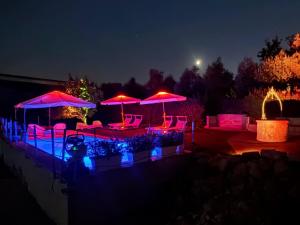 a patio with umbrellas and chairs at night at Villa Malvasio Pool and Jacuzzi Room Sassari in Sassari
