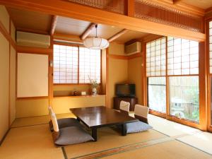a dining room with a table and chairs and windows at Fukashiso in Matsumoto
