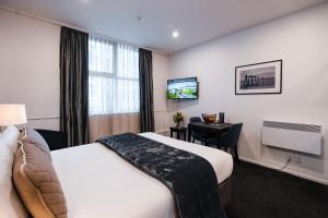 a hotel room with a bed and a desk and a television at Gilmer Apartment Hotel in Wellington