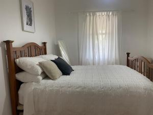 a bedroom with a bed with pillows and a window at Tea Tree Cottage - Heart of Port Elliot in Port Elliot