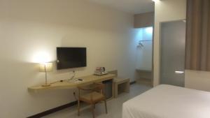 a bedroom with a desk with a television and a bed at Sweet Garden Guest House in Malang