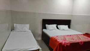 two beds in a small room with a red blanket at Krishan Kripa Dham Near Banke Bihari ji Temple in Vrindāvan