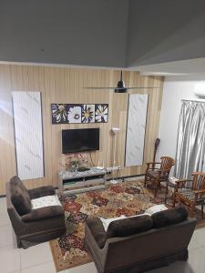 a living room with a couch and chairs and a television at The Cermai Homestay in Sungai Buluh