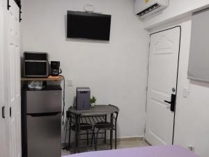een kleine keuken met een tafel en een tv aan de muur bij Pequeño Alojamiento in Cancun