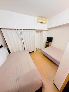 a small room with two beds and a tv at Tokyo West Shinjuku close to Shinjuku Chuo Park in Tokyo