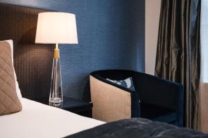 a room with a bed and a lamp and a chair at Gilmer Apartment Hotel in Wellington