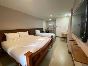 a bedroom with two beds and a flat screen tv at Thebedkolok resort in Sungai Kolok