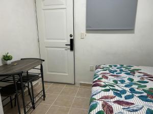 a room with a bed and a table and a door at Pequeño Alojamiento in Cancún