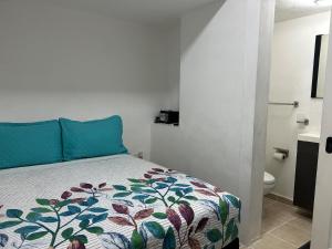 a bedroom with a bed with blue pillows and a toilet at Pequeño Alojamiento in Cancún