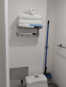 a bathroom with a toilet and towels on a shelf at Pequeño Alojamiento in Cancún