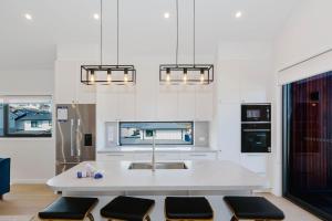 a white kitchen with a sink and a table at Rawson Retreat - Spa, EV outlet and Premium Luxury in Jindabyne