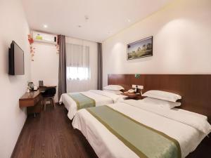 a hotel room with two beds and a desk at Vatica Shanghai Jiading District Anting Metro Station Moyu Road Hotel in Anting Zhan