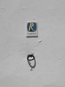 a sign on the side of a white wall at La Casa de Corruco in Casabermeja