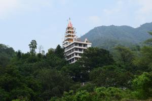 a building on top of a hill with trees at Hotel Moksha in Rishīkesh