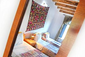 a mirror reflecting a bedroom with two beds and a window at Boutique Old City in Bukhara