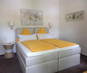 ein Schlafzimmer mit einem weißen Bett mit gelber Bettwäsche in der Unterkunft Gästehaus Kehne in Horn-Bad Meinberg