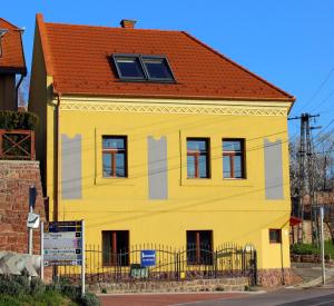 une maison jaune avec un toit rouge dans l'établissement Vöröskő Apartman Alsóörs, à Alsóörs