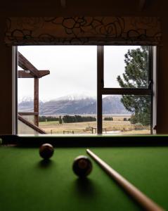 a pool table with three balls in front of a window at Mt Potts Lodge in Ashburton Lakes