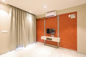 Habitación con pared de ladrillo rojo y TV. en The Marbella Beach Resort, en Diveagar