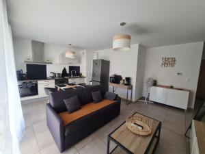 a living room with a couch and a kitchen at L'instant Léman - T2 3 étoiles à 5min de Thonon et Evian avec terrasse et jardin à 100m du lac in Publier
