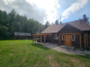 a wooden cabin with a large yard in front of it at Leniuszkowo Święty Spokój in Zaleszany