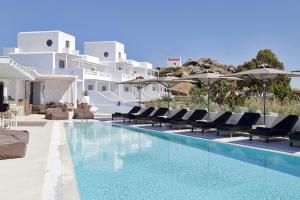 uma piscina com cadeiras e guarda-sóis ao lado de um resort em Livin Mykonos Hotel em Míconos