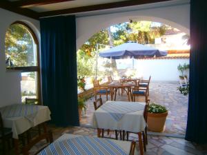 un patio con mesas, sillas y una sombrilla en Bed & Breakfast Pansion Rade, en Pirovac
