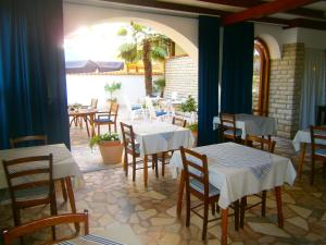 un restaurante con mesas y sillas blancas y un patio en Bed & Breakfast Pansion Rade, en Pirovac