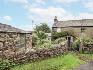 an old stone house with a stone wall at Old Cottage in Ulverston