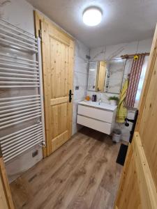a bathroom with a sink and a wooden door at Apartments Pajek & Pajčevina on the Hayrack in Dobje pri Lesičnem