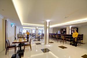 アジュマーンにあるLuxury 4 Bedroom Apt with Complimentary Access to Hotel Private Beach,GYM&Swimming Poolのテーブルと椅子のある部屋に2人が立っているレストラン