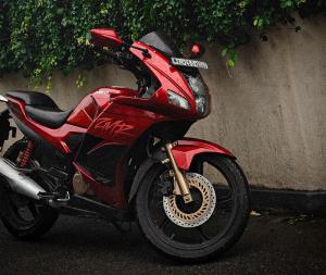 a red motorcycle parked next to a wall at AdTaken in Ernakulam