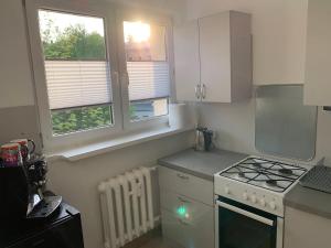 a small kitchen with a stove and two windows at Apartament na Chrobrego in Cieszyn +2 photos