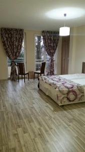a bedroom with a bed and chairs and windows at Park View Studios in Sandanski