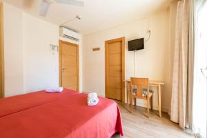 a bedroom with a red bed and a television at Hostal Residencia Europa Punico in Ibiza Town