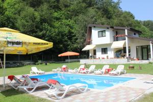una piscina con sillas, una sombrilla y una casa en Casuta Didi, en Brezoi